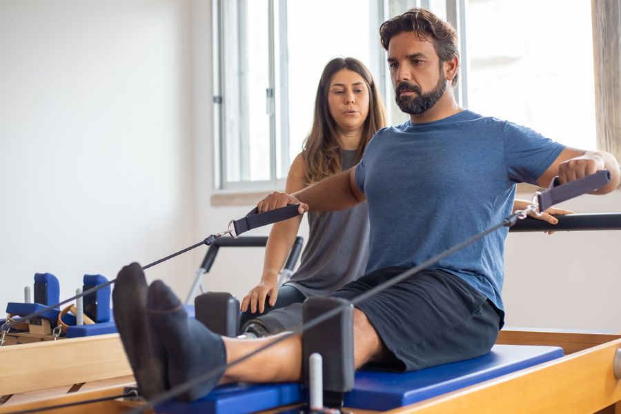 A patient exercising on a reformer during a clinical Pilates session