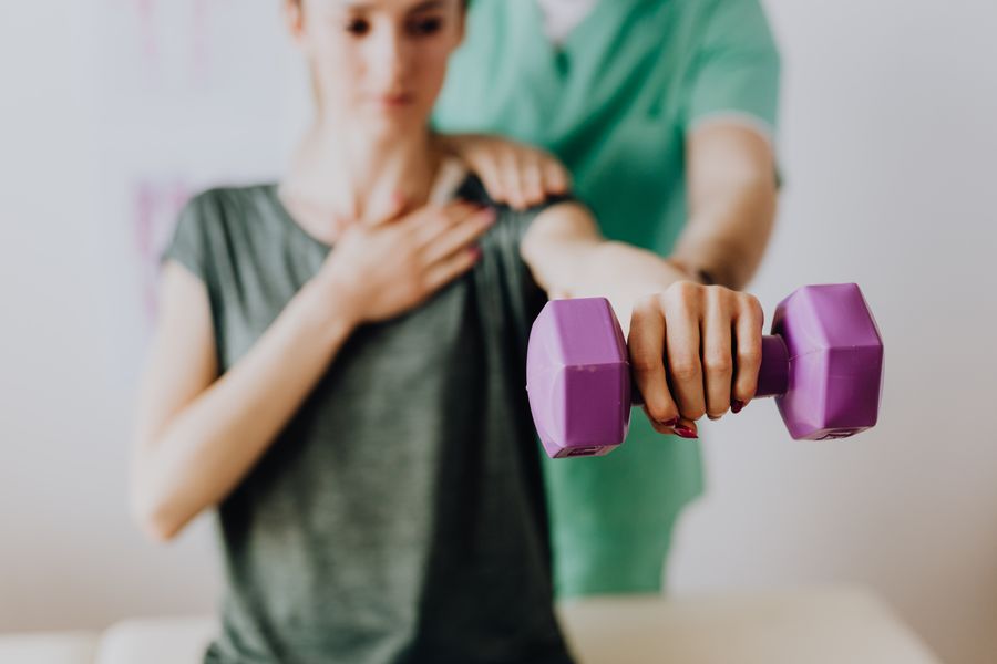 A physiotherapist guiding a patient through shoulder rehabilitation exercises